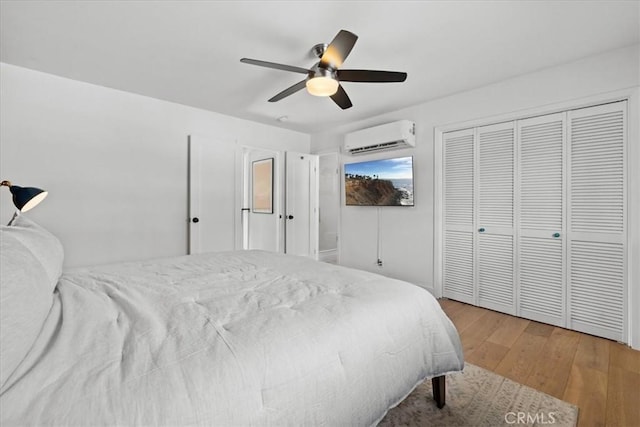 bedroom featuring ceiling fan, an AC wall unit, a closet, and wood finished floors