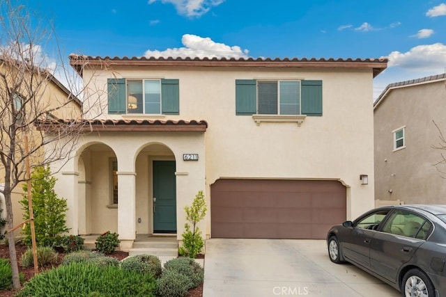 mediterranean / spanish house featuring a garage, concrete driveway, and stucco siding