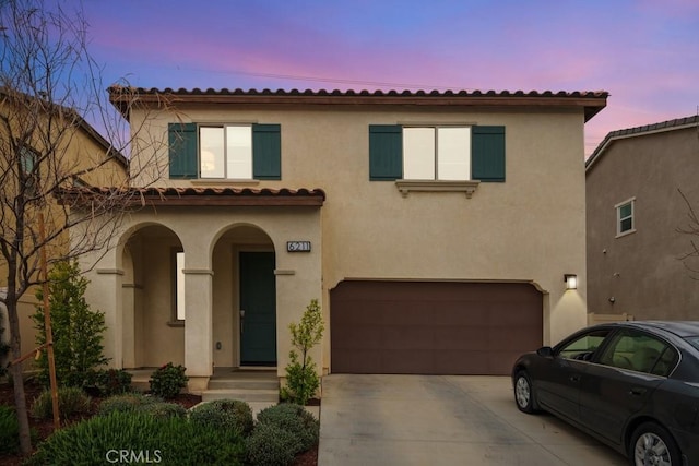 mediterranean / spanish-style home featuring an attached garage and stucco siding