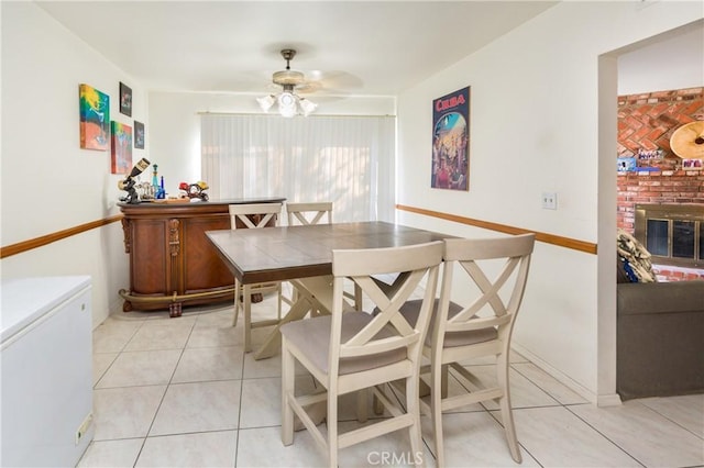 dining room featuring light tile patterned floors, ceiling fan, and a fireplace