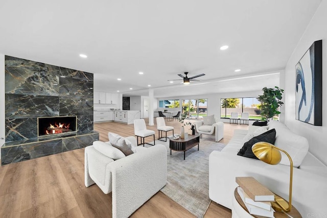 living room with light wood finished floors, recessed lighting, a ceiling fan, and a high end fireplace