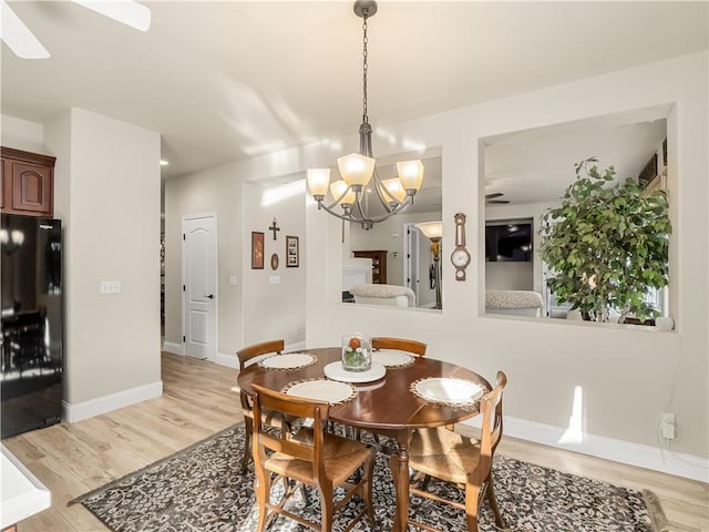 dining area featuring baseboards, an inviting chandelier, and light wood-style floors