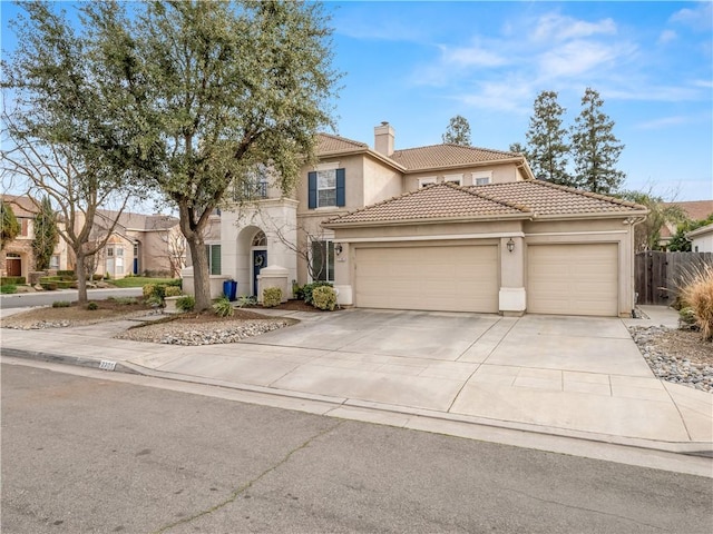 mediterranean / spanish house with an attached garage, a tile roof, concrete driveway, and stucco siding