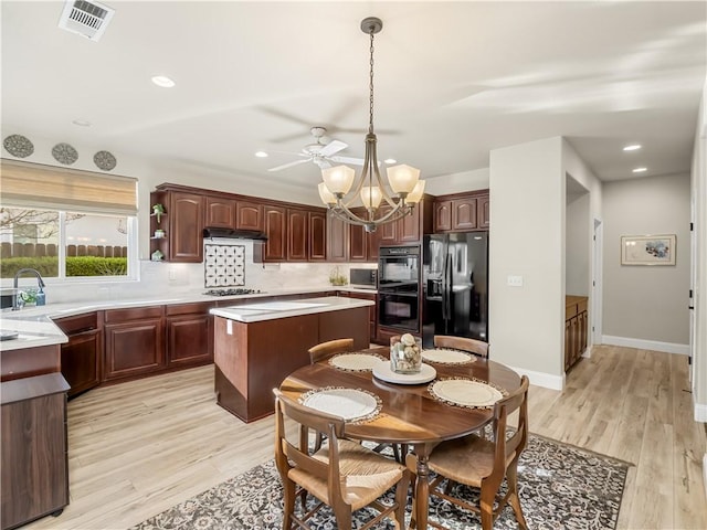 kitchen featuring visible vents, light countertops, light wood-type flooring, backsplash, and black appliances