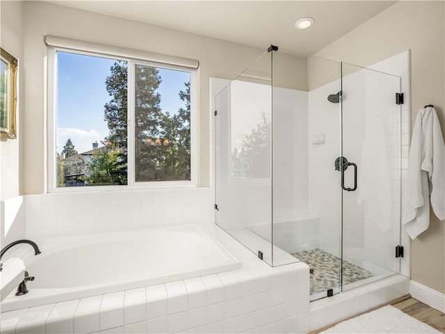 bathroom with a stall shower, a garden tub, and wood finished floors