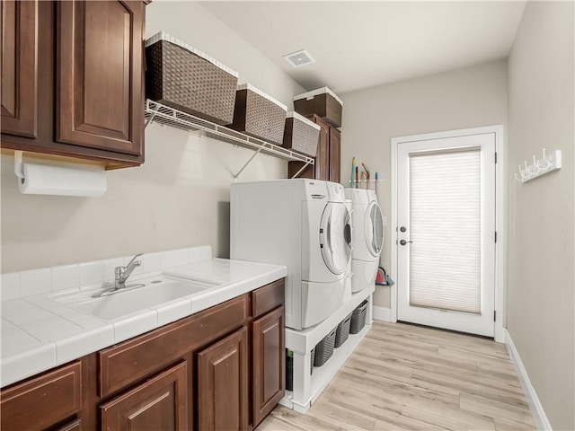 2705 E Ryan Ln, Fresno, CA 93720 - clothes washing area featuring washing machine and clothes dryer, cabinet space, light wood finished floors, and baseboards