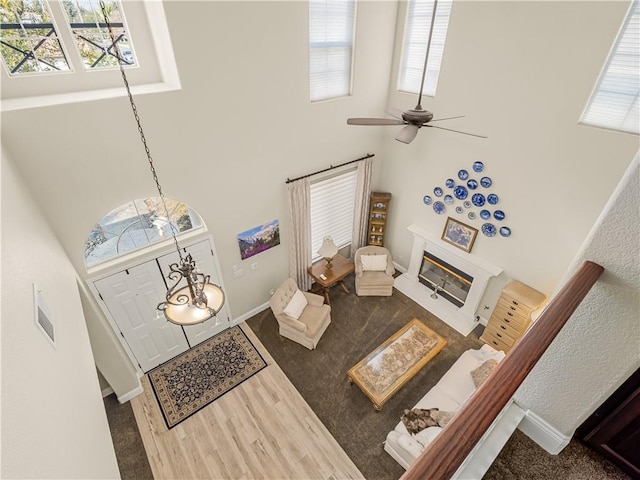 living area with a glass covered fireplace, a towering ceiling, and a healthy amount of sunlight