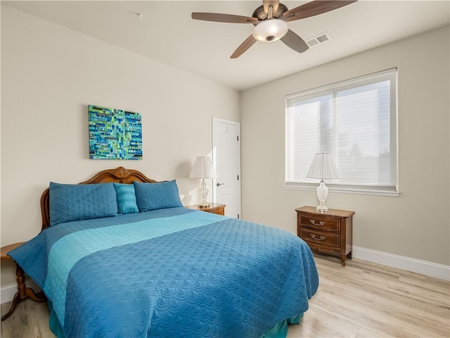 bedroom featuring baseboards, visible vents, ceiling fan, and light wood finished floors