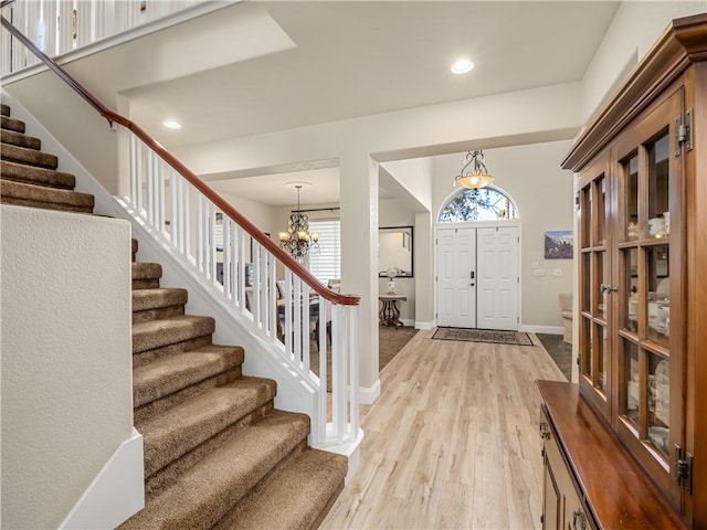 foyer featuring recessed lighting, baseboards, stairs, light wood finished floors, and an inviting chandelier