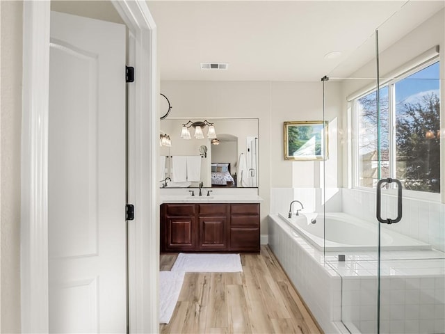 bathroom featuring visible vents, ensuite bath, wood finished floors, a garden tub, and vanity