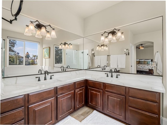 ensuite bathroom with double vanity, connected bathroom, and a sink