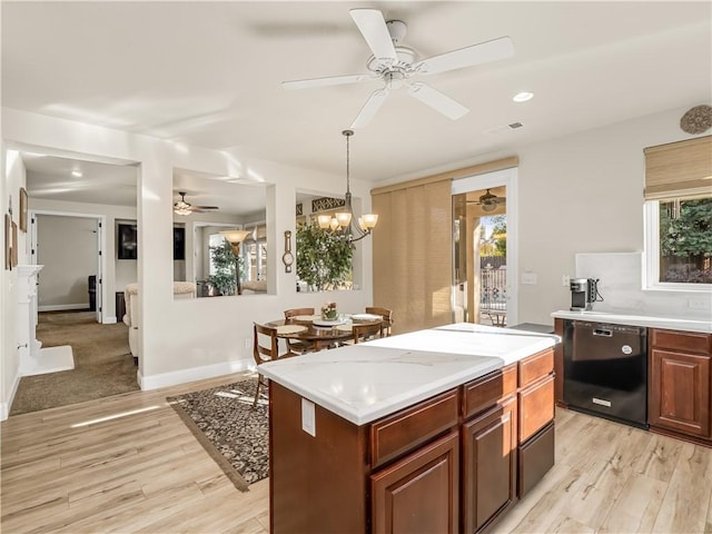 kitchen featuring dishwasher, light countertops, light wood-style flooring, and a center island