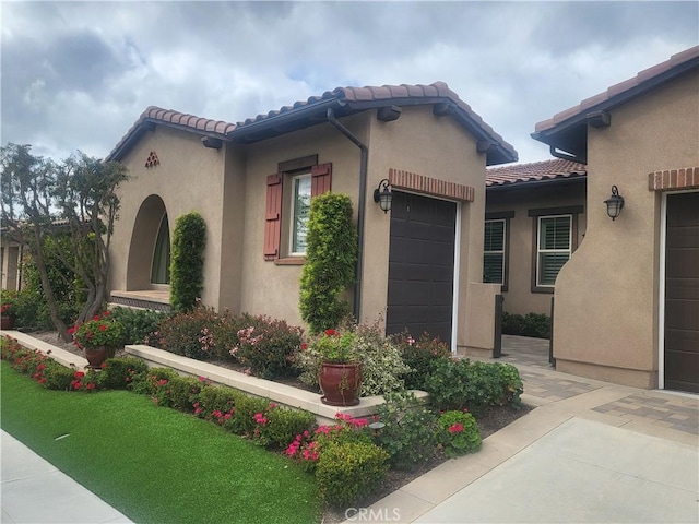 exterior space featuring a tiled roof, an attached garage, and stucco siding