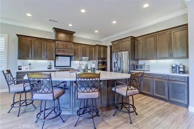 kitchen featuring visible vents, dark brown cabinets, stainless steel appliances, and light countertops