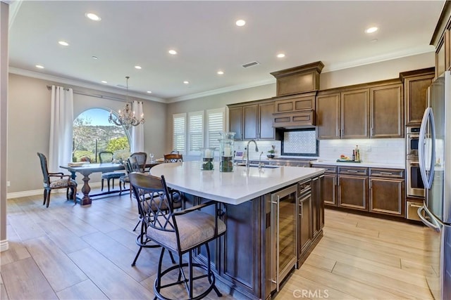 kitchen featuring tasteful backsplash, a breakfast bar, light countertops, stainless steel refrigerator, and a sink