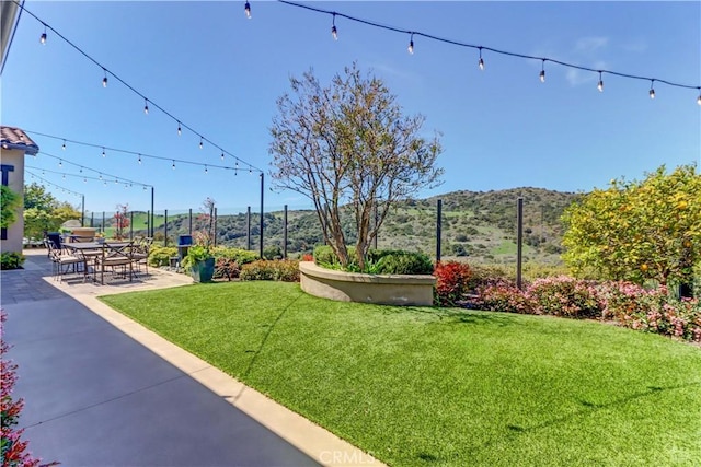view of yard featuring a mountain view, fence, and a patio