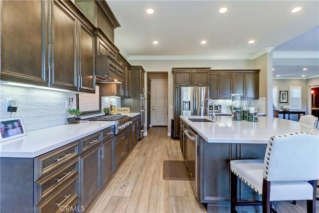 kitchen with light countertops, ornamental molding, appliances with stainless steel finishes, ventilation hood, and a kitchen breakfast bar