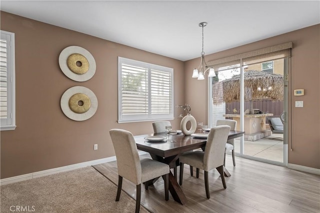 dining space featuring a notable chandelier, light wood finished floors, and baseboards