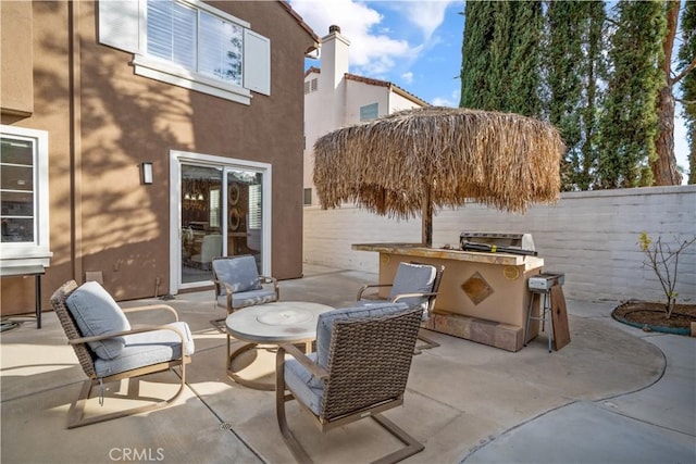 view of patio / terrace featuring fence, outdoor dry bar, and exterior kitchen