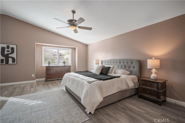 bedroom with vaulted ceiling, baseboards, and wood finished floors