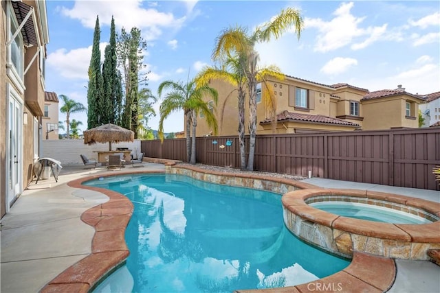 view of pool with a fenced backyard, a pool with connected hot tub, and a patio