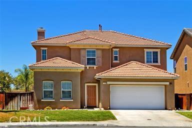 mediterranean / spanish home featuring an attached garage, a tiled roof, driveway, stucco siding, and a chimney