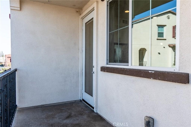 property entrance featuring a balcony and stucco siding