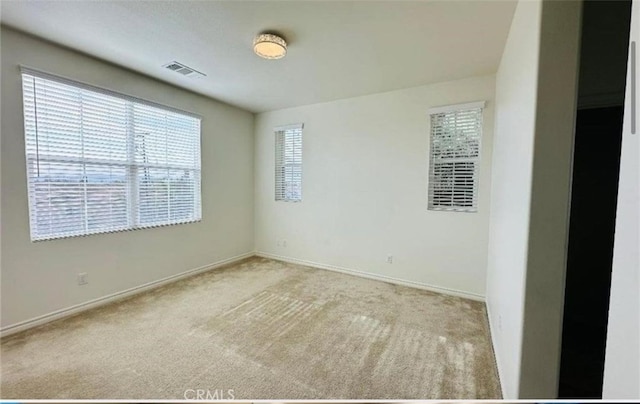 carpeted empty room featuring baseboards and visible vents