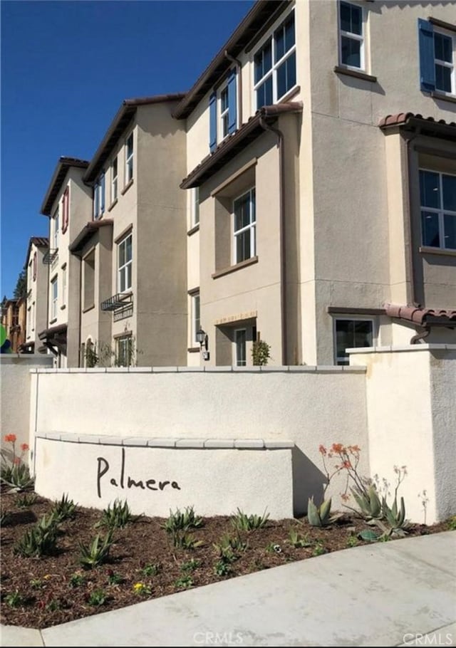 view of side of property featuring a fenced front yard, a residential view, and stucco siding