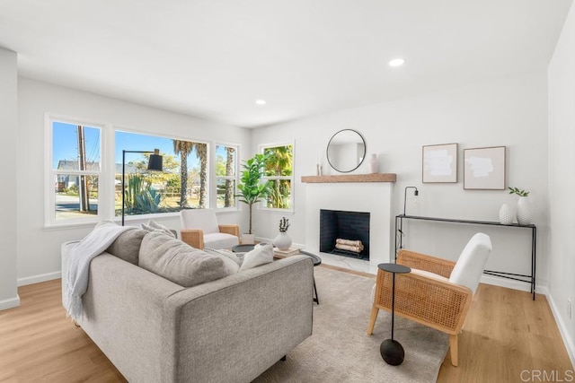 living area featuring light wood-style floors, a fireplace with flush hearth, and recessed lighting