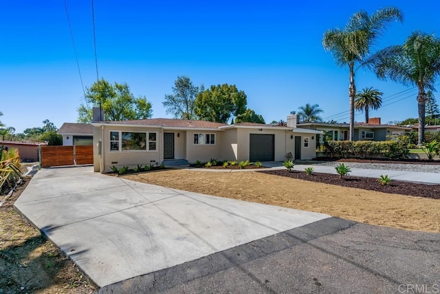 ranch-style home featuring an attached garage, fence, driveway, stucco siding, and a chimney