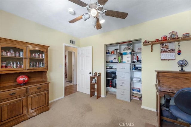 home office featuring a ceiling fan, visible vents, light carpet, and baseboards