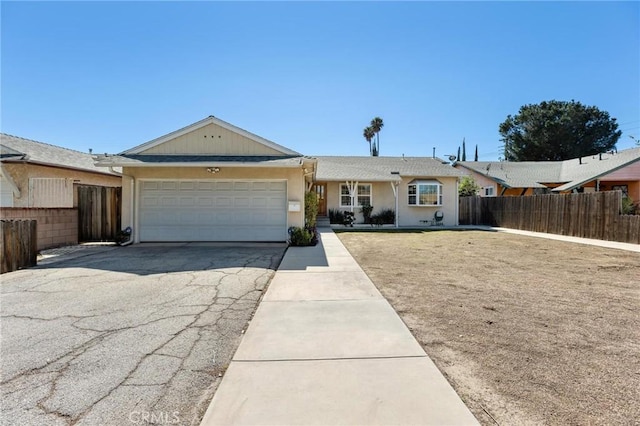 single story home with driveway, an attached garage, and fence