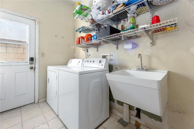 clothes washing area featuring light tile patterned floors, laundry area, separate washer and dryer, and a sink