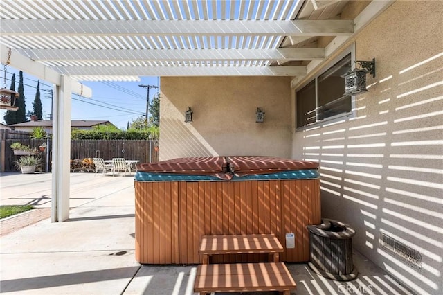 view of patio featuring a hot tub, fence, and outdoor dining area