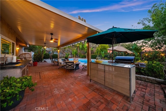 patio terrace at dusk featuring an outdoor pool, area for grilling, ceiling fan, a grill, and a sink