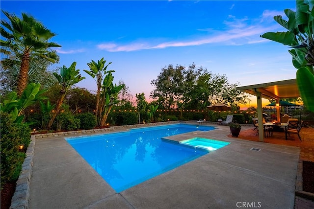 pool at dusk featuring a patio area and an outdoor pool