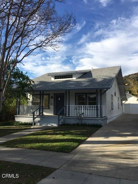 bungalow with a porch, a front lawn, and a shingled roof