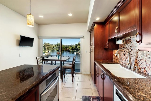 kitchen with dark stone countertops, pendant lighting, a sink, and decorative backsplash