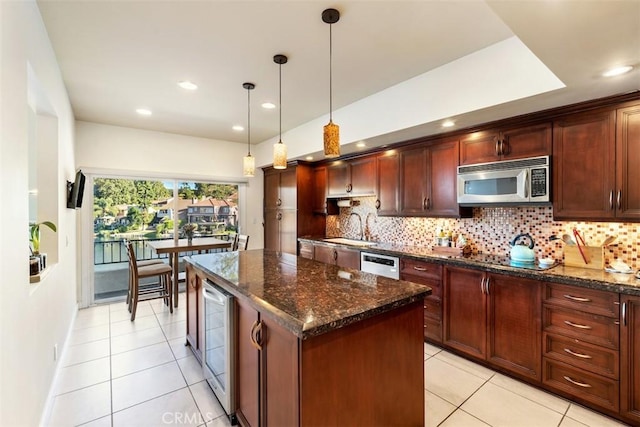 kitchen featuring tasteful backsplash, wine cooler, stainless steel microwave, and a sink