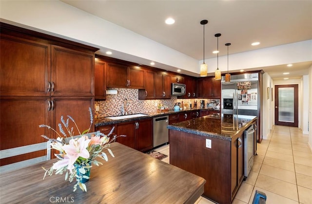 kitchen with light tile patterned flooring, stainless steel appliances, a kitchen island, a sink, and decorative backsplash