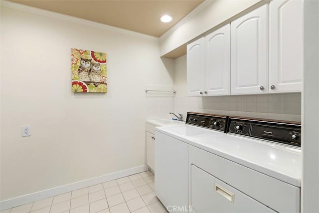 washroom featuring crown molding, cabinet space, washing machine and dryer, a sink, and baseboards