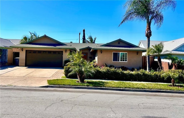 ranch-style house with concrete driveway, fence, an attached garage, and stucco siding