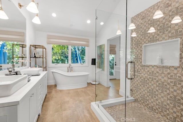 full bath featuring lofted ceiling, a freestanding tub, a sink, double vanity, and a stall shower