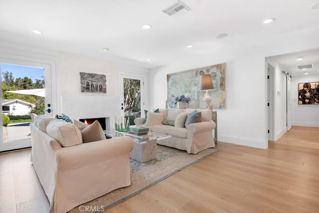 living room featuring recessed lighting, light wood-style flooring, and a healthy amount of sunlight