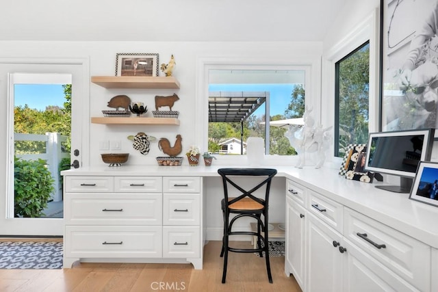 home office featuring light wood finished floors, built in study area, and a healthy amount of sunlight