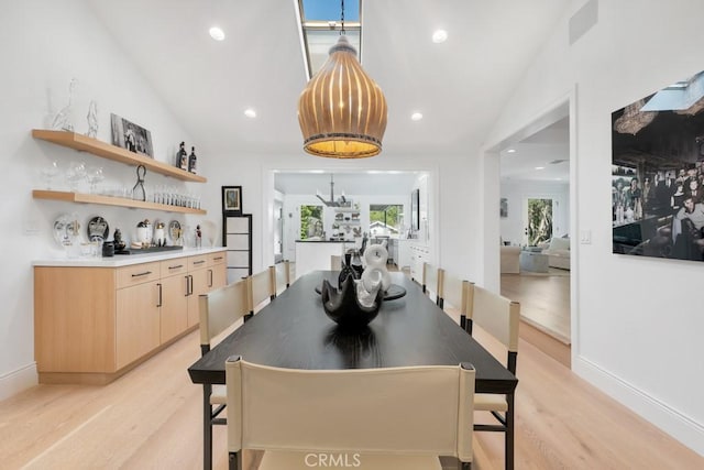 dining area with lofted ceiling, recessed lighting, light wood-type flooring, and an inviting chandelier