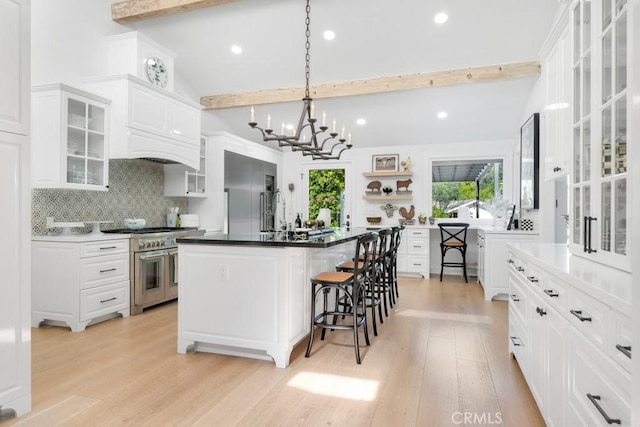 kitchen with vaulted ceiling with beams, light wood-style flooring, backsplash, and high quality appliances