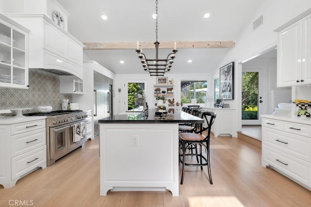 kitchen with a sink, a kitchen breakfast bar, white cabinets, double oven range, and glass insert cabinets