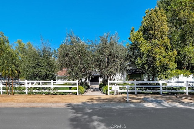 view of property hidden behind natural elements with a fenced front yard